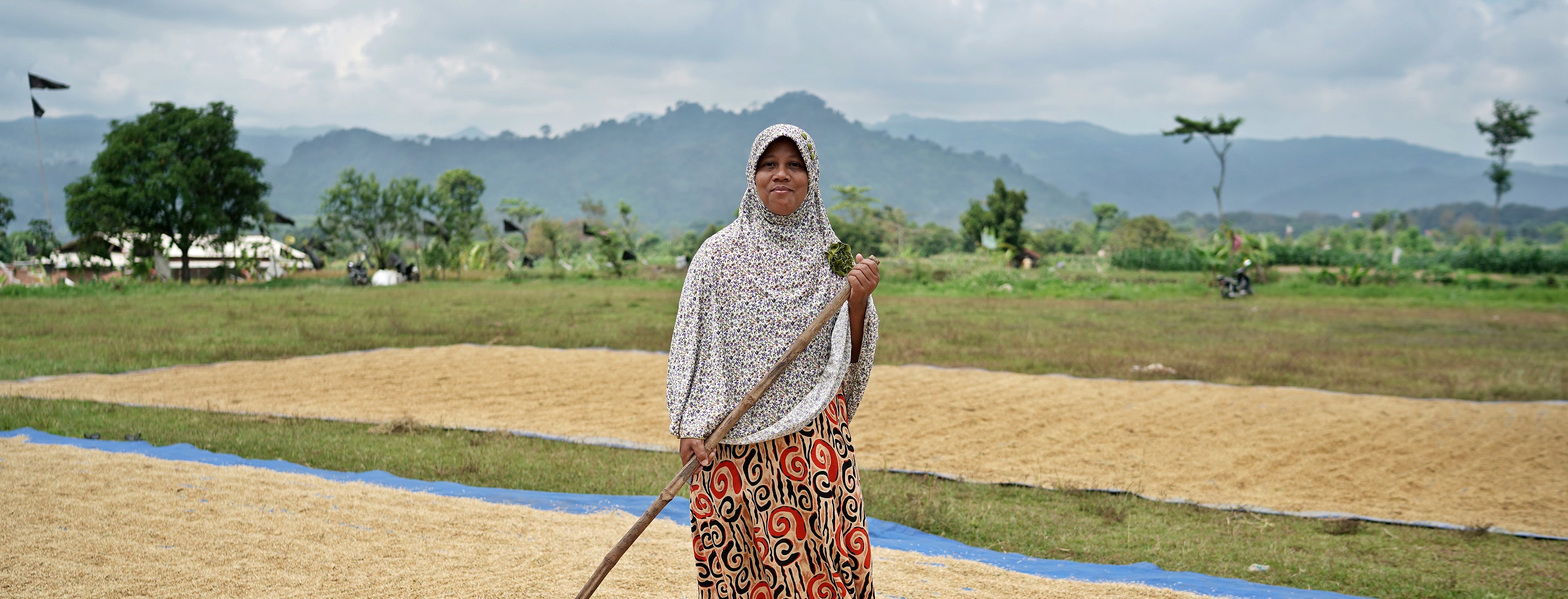 a woman poses while drying grain in the middle of the field